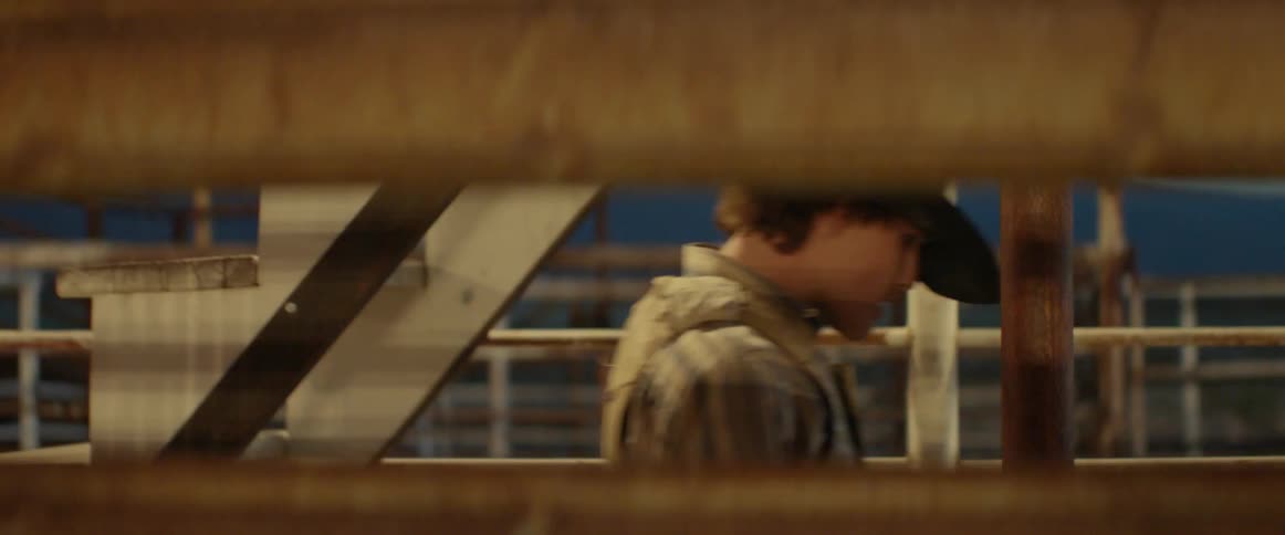 A cowboy walks next to a fence