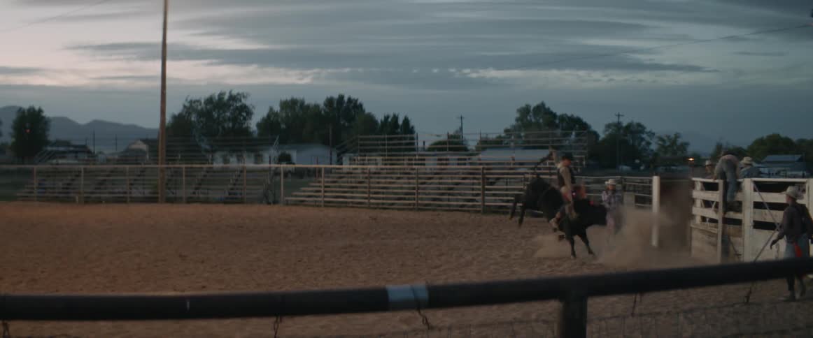 A man is riding a bull inside a bull ring