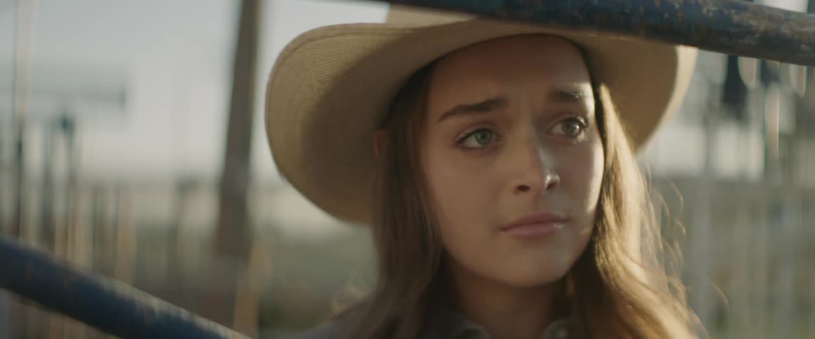 A cowgirl looks worried while standing outside