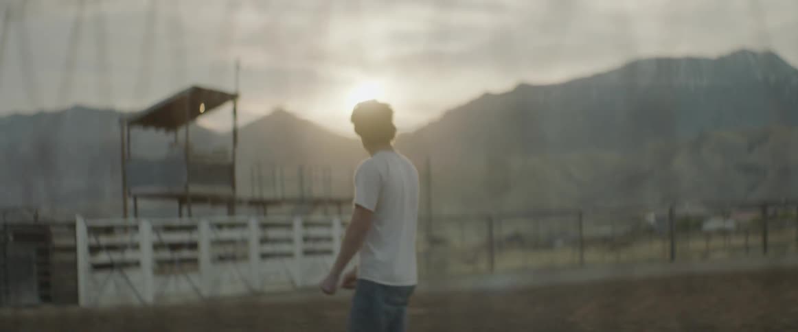 Man stands in a corral at sunset