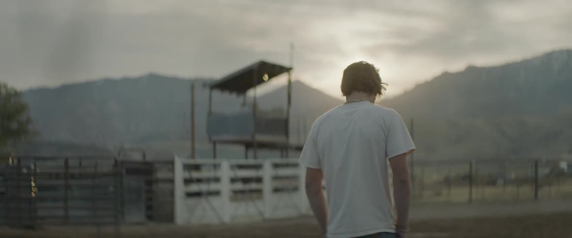 Man stands in an empty rodeo arena at sunrise