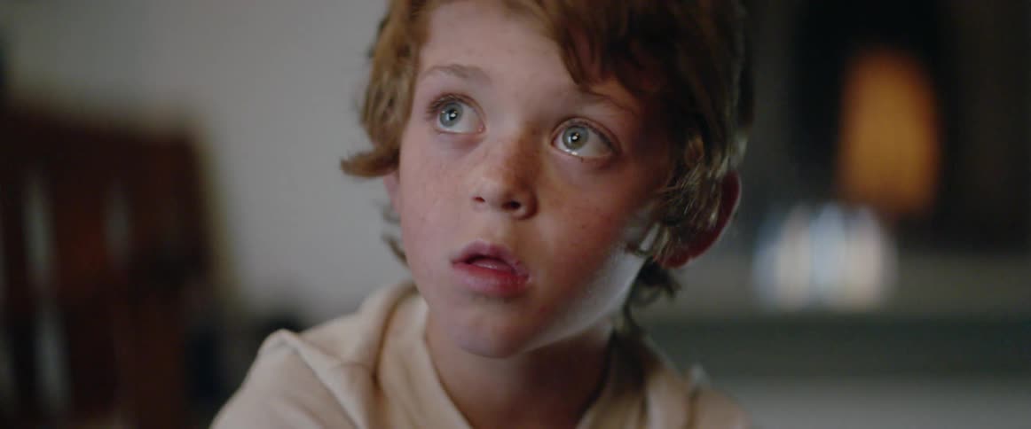 A young boy’s face glows as he watches television, completely mesmerized