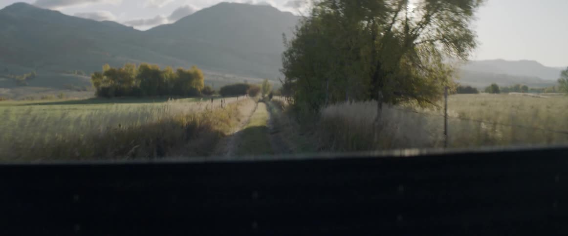 A pickup truck drives down a dirt road