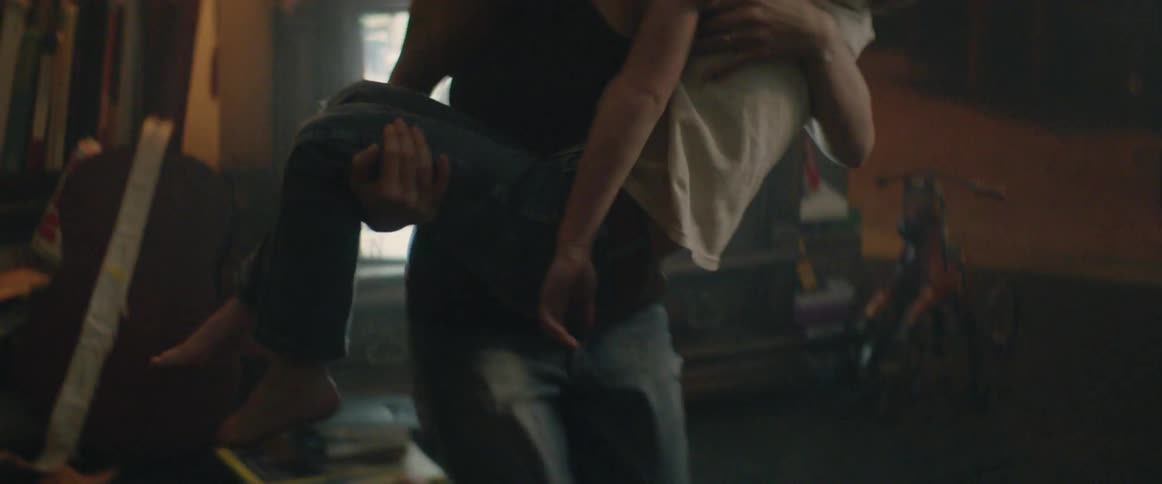 A woman picks up her sleeping child by the television