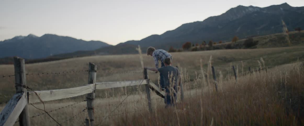Children walk over to a fence and climb over together