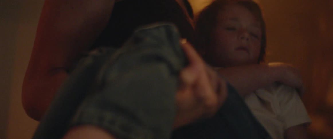 Woman carries sleeping boy through the room