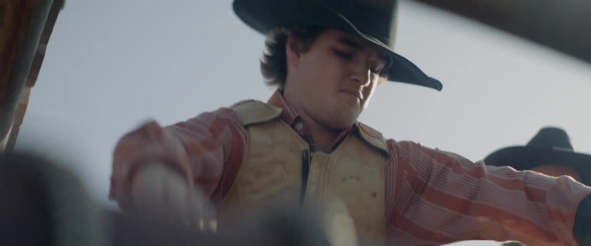 A rodeo rider gets onto the animal in the chute