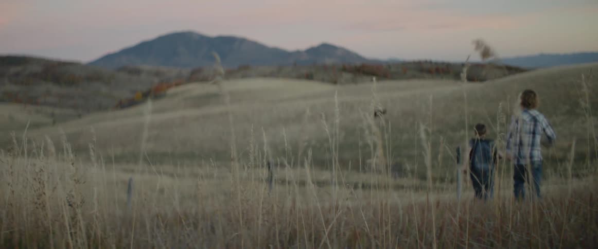 A kid is running through the grass of a pasture