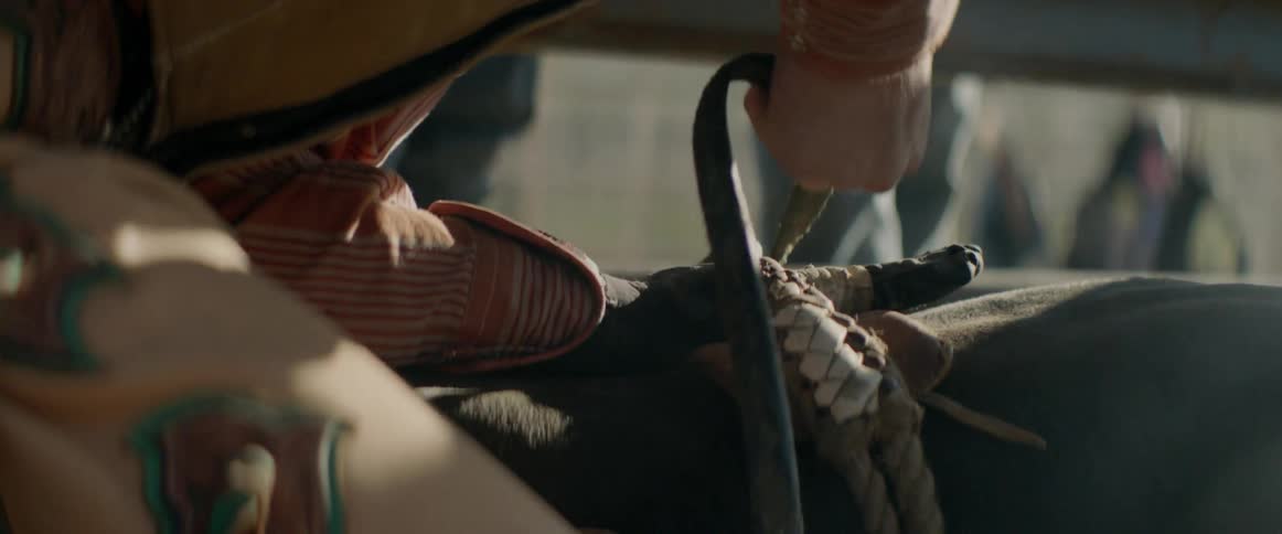 A cowboy wraps the rope from the bull around his hand