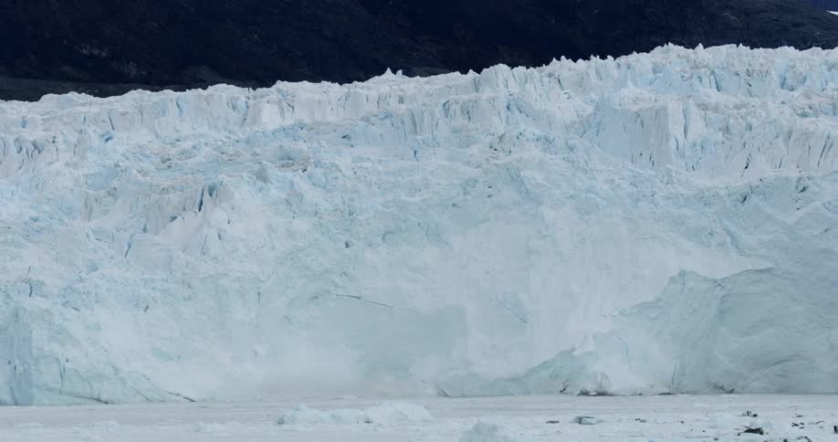 A large wall of ice is being filmed from a boat