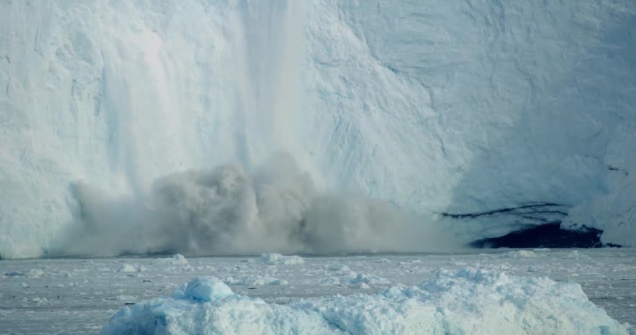 Snow and ice calves off a glacier and crashes into the ocean