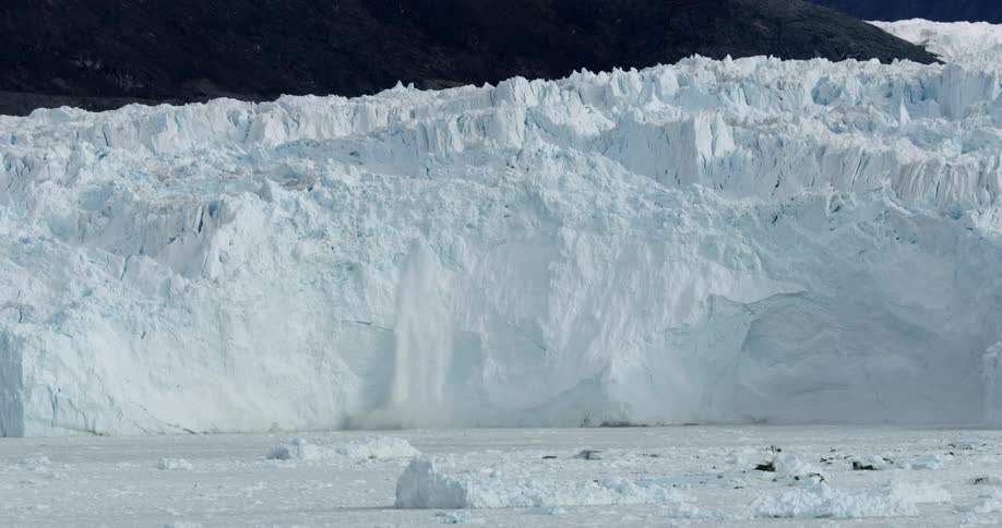 A portion of an iceberg breaks free and falls downward