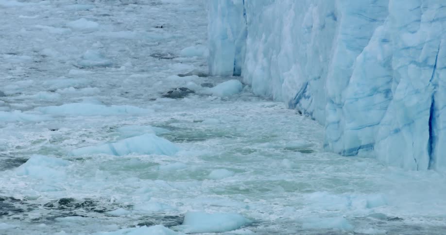 The tide rolls at the base of a glacier during the day