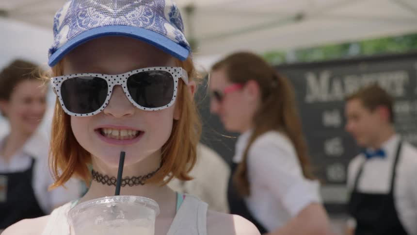 Girl drinks lemonade near a lemonade stand