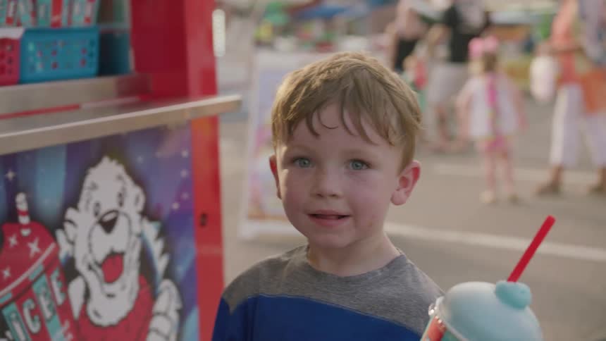 A child receives a blue icee at a fair
