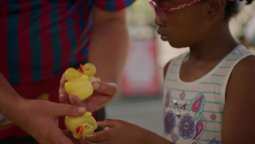 Little girl takes a yellow rubber duck from a tub of water