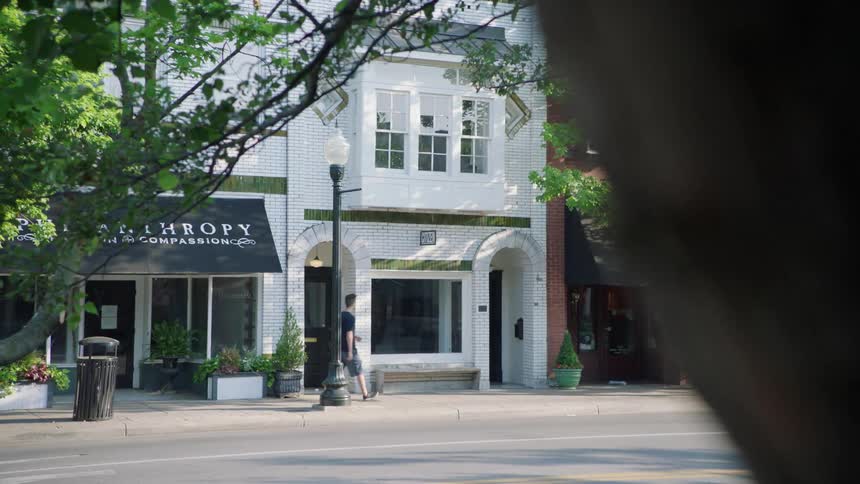 Man walking down a city street and then entering a doorway on his left