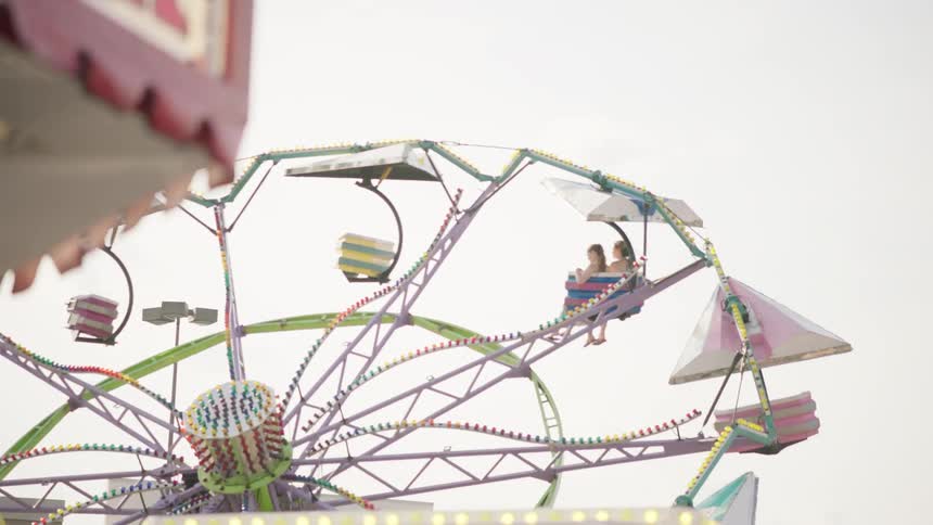 A tilt-a-whirl rotates at a county fair