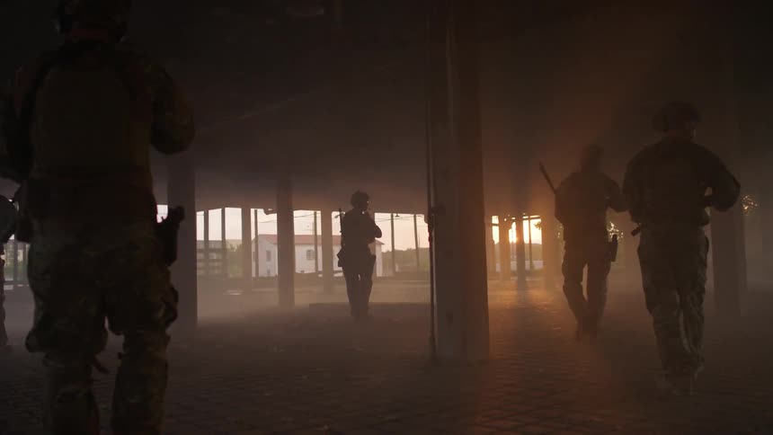 Military soldiers patrol an empty warehouse