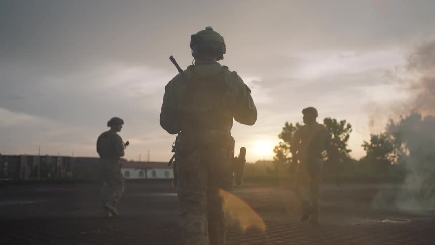 The soldiers march forward over the field at sunset