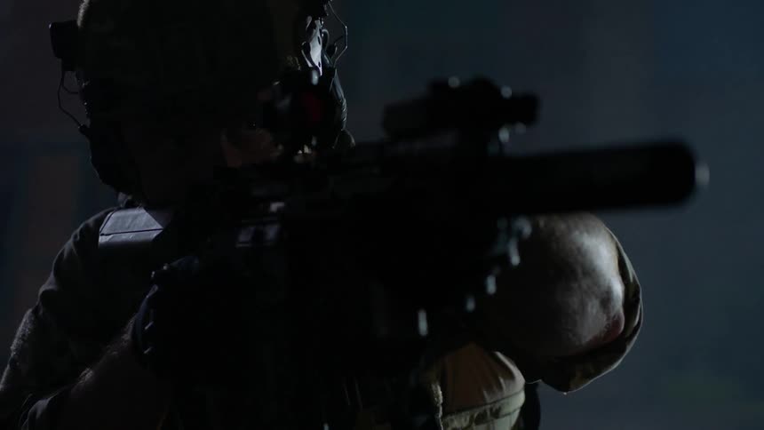 Soldier aims a gun while wearing a helmet