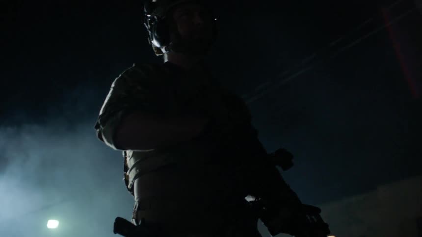 A soldier patrols a smoky area at night