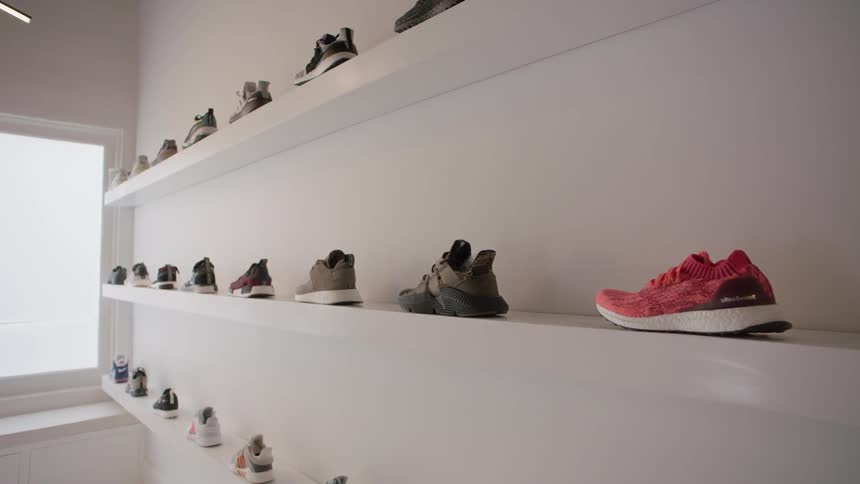 Many sneakers sitting on three shelves in single rows