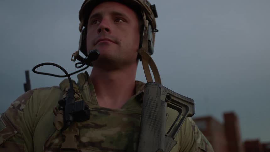 Soldier stands on a rooftop looking in the distance