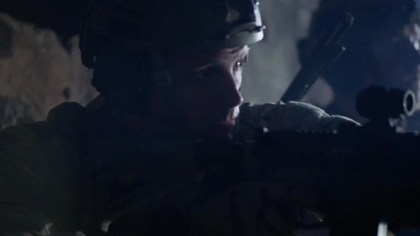 Soldiers fire their rifles outside in the evening