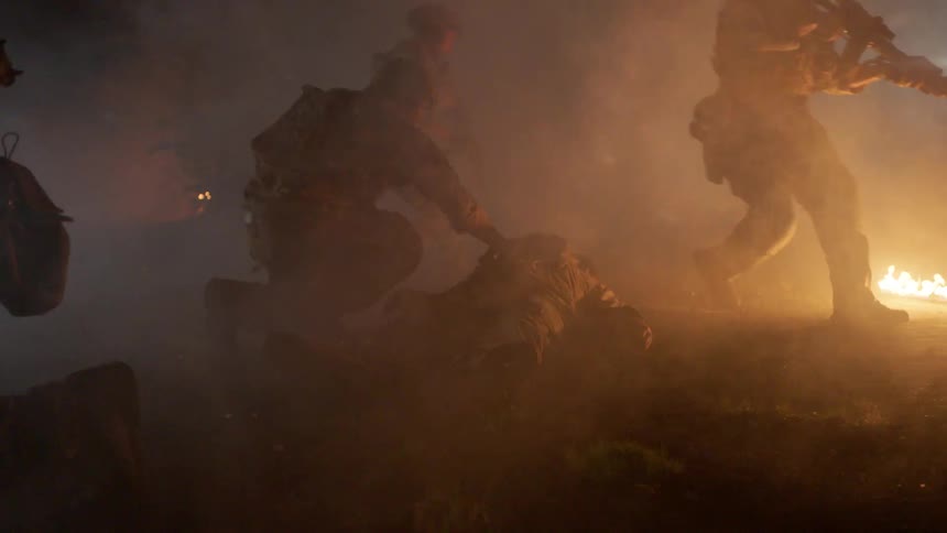 Soldiers approach a fallen comrade in a war zone