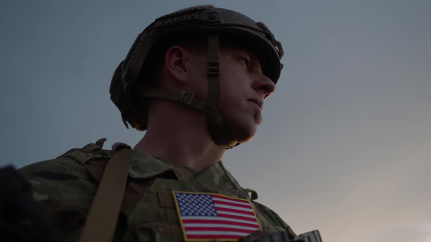 America soldier stands outside with a gun at sunset