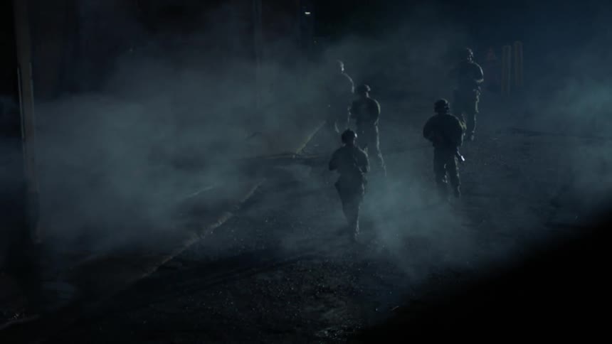 Soldiers patrol a hazy street in the evening