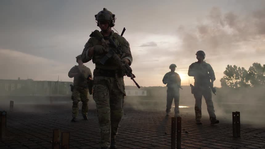 Soldiers patrol a smoky area at sunset