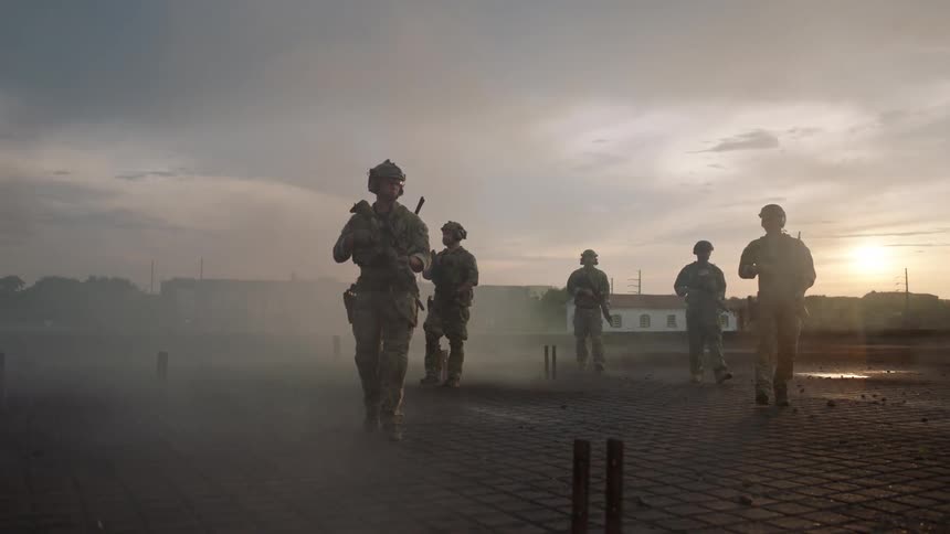 Soldiers walking through a smoky area at sunset