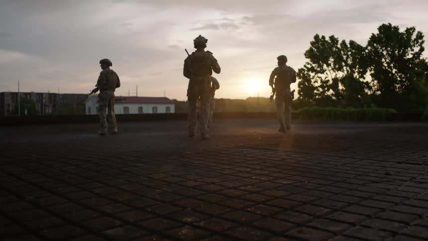 Soldiers walk across a tile courtyard at sunset
