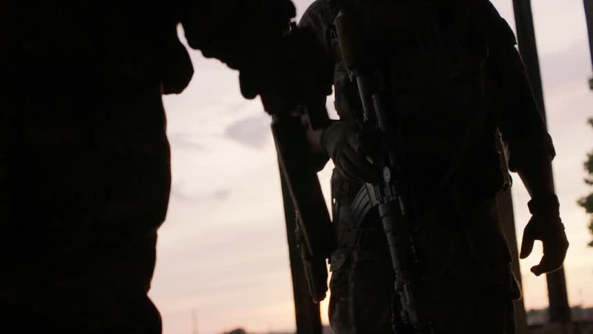 Soldiers standing outdoors with weapons on a cloudy day