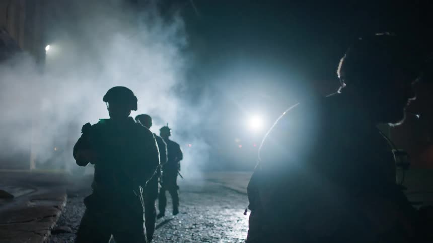 Soldiers patrol a town at night