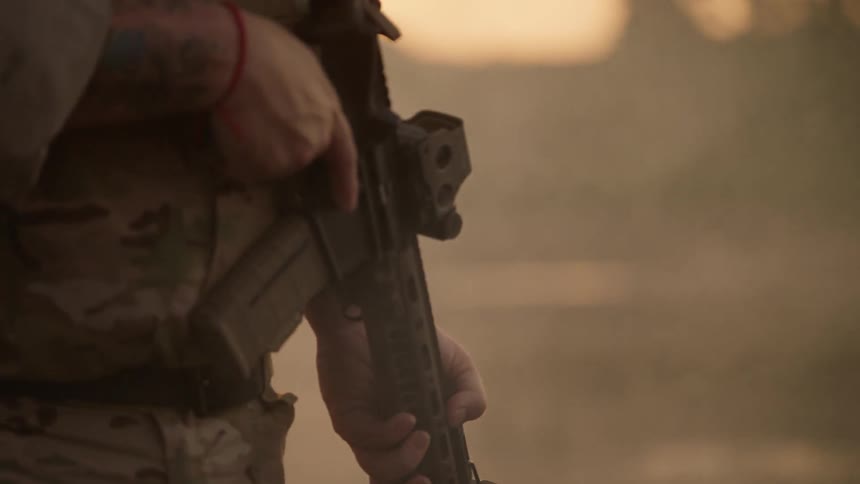 A soldier patrols a smoky area at sunset