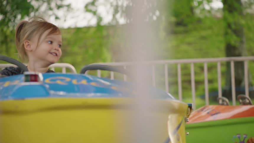 Little girl is smiling while riding on carnival ride at fair