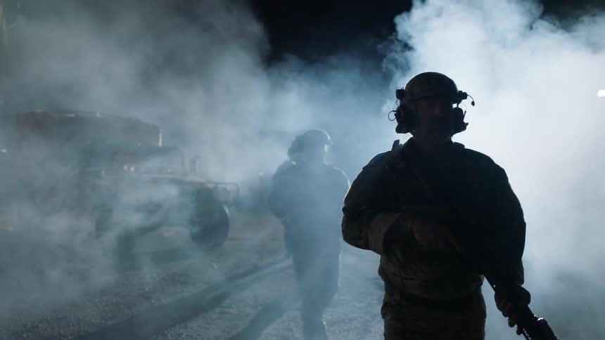 Soldiers patrol a smoky area at night