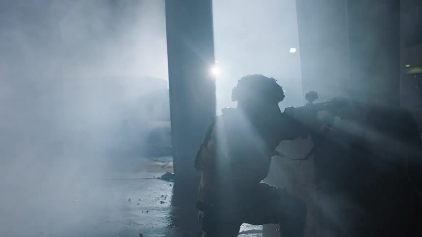 Soldier kneels with a gun in a smoky room