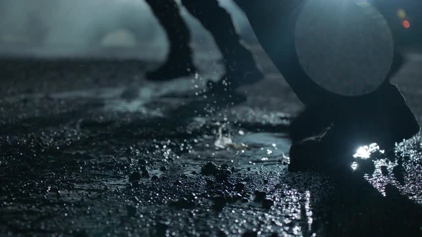 Soldiers march through a wet road