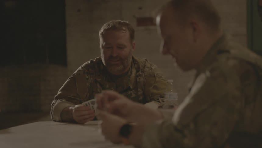 Soldiers sit at a table playing cards