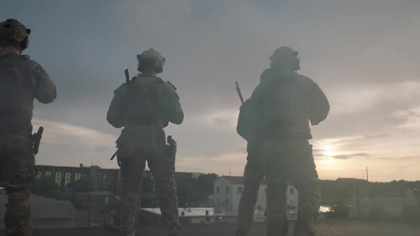 Soldiers walk on top of a roof through the haze
