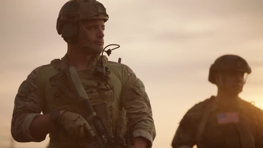 Two uniformed men hold guns and stand outside