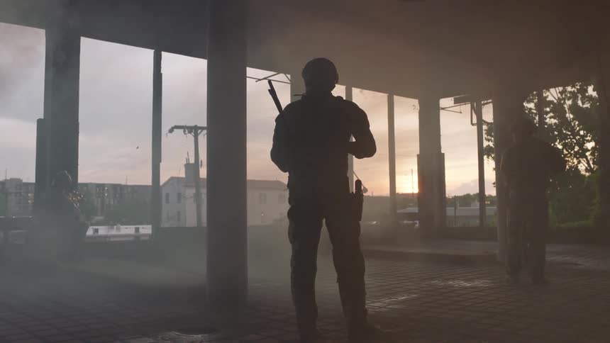 Two soldiers stand guard in a town at sunset