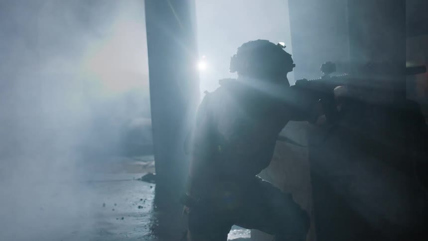 A soldier fires his gun in a smoky area