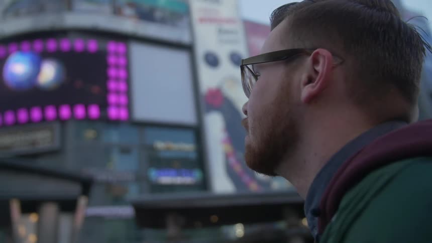 A man stands in front of city buildings
