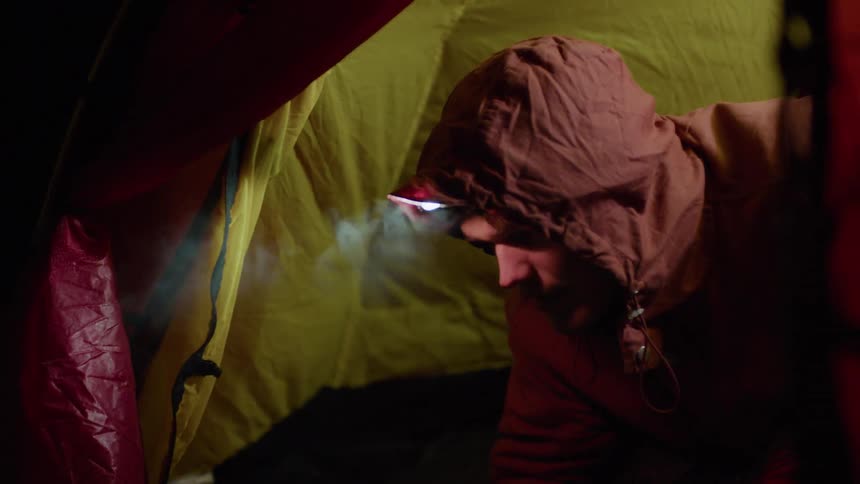 Man wears a headlamp in a tent at night