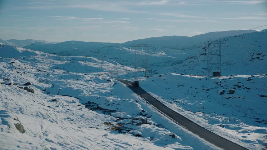 A car drives down the road surrounded by snow